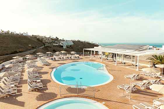 Uima-allasalue, jossa on aurinkotuoleja ja -varjoja terassilla, merinäköalalla. (Tekoälyn luoma teksti)