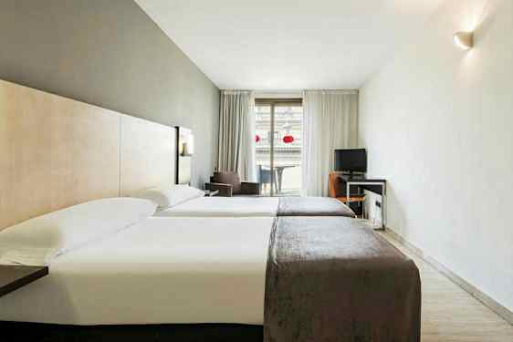 Hotellihuone, jossa on kaksi yhden hengen sänkyä ja työpöytä parvekkeen vieressä. (Tekoälyn luoma teksti)