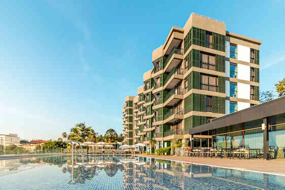 Moderni rakennus uima-altaan vieressä kirkkaan sinisen taivaan alla. (Tekoälyn luoma teksti)