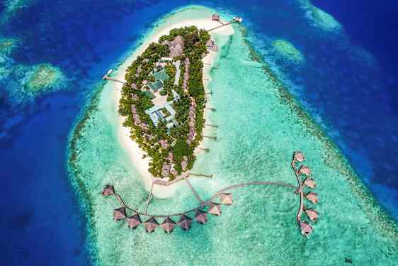 Ilmakuva trooppisesta saaresta, jossa rakennuksia turkoosinsinisen veden ympäröimänä. (Tekoälyn luoma teksti)