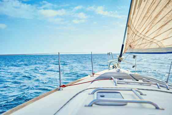 Lähikuva purjeveneen keulakannesta, valkoinen purje ja sininen meri taustalla. (Tekoälyn luoma teksti)