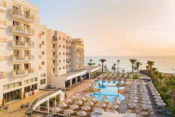 Hotelli jossa parvekkeita, uima-allasalue ja merinäköala taustalla. (Tekoälyn luoma teksti)