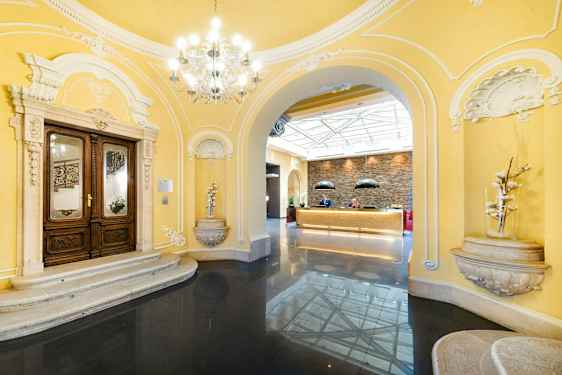 Sisäänkäyntialue klassisilla arkkitehtonisilla yksityiskohdilla ja vastaanotto valoisassa ympäristössä. (Tekoälyn luoma teksti)