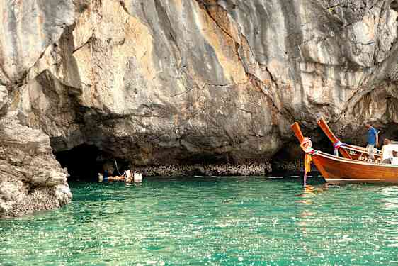 Ihmiset uivat vedessä kallion luona, ja kaksi puista alusta kelluu lähellä. (Tekoälyn luoma teksti)