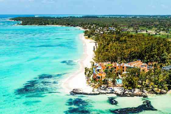 Hiekkaranta turkoosilla vedellä ja hotellit vehreyden ympäröiminä. (Tekoälyn luoma teksti)