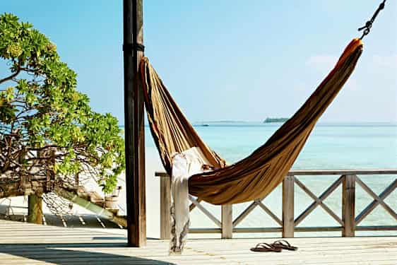 Riippumatto roikkuu kahden tolpan välissä verannalla, josta on näkymä turkoosiin mereen. (Tekoälyn luoma teksti)