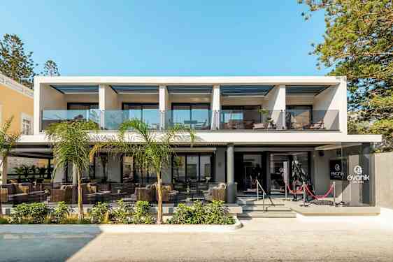 Nykyaikainen hotellirakennus lasikaiteilla ja ulkokalusteilla sisäänkäynnin luona. (Tekoälyn luoma teksti)