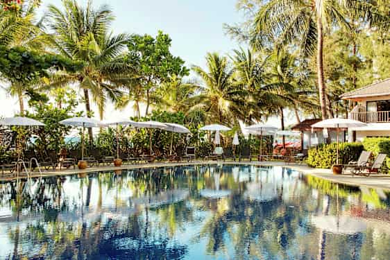 Ulkouima-allas, jota ympäröivät aurinkotuolit ja aurinkovarjot, taustalla palmuja. (Tekoälyn luoma teksti)