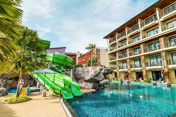 Hotellin uima-allas, jossa on vihreät liukumäet ja rakennus taustalla. (Tekoälyn luoma teksti)