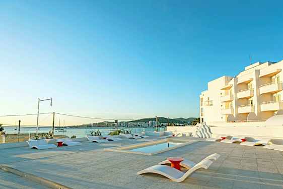 Ulkoaltaan alue nykyaikaisilla aurinkotuoleilla, näkymä merelle ja valkoisia rakennuksia taustalla. (Tekoälyn luoma teksti)