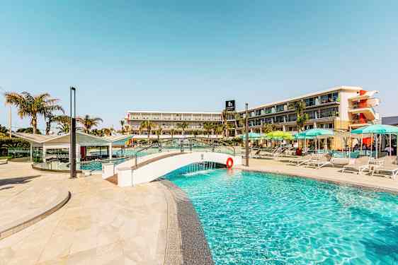 Kuva uima-altaasta, jossa on pieni silta ja hotellirakennus taustalla. (Tekoälyn luoma teksti)