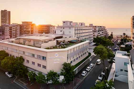 Hotellirakennus meren rannalla muiden rakennusten ympäröimänä auringonlaskussa. (Tekoälyn luoma teksti)