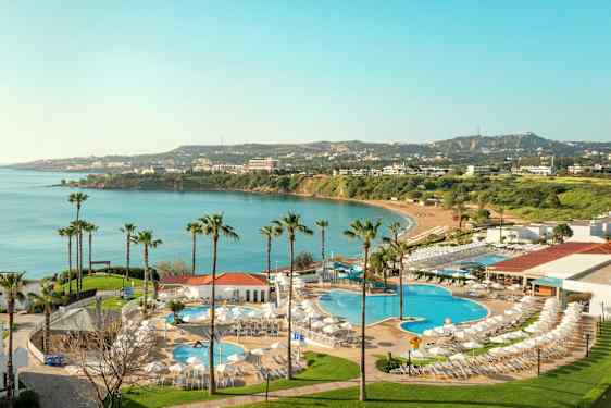 Näkymä hotellialueelle, jossa on uima-altaita ja näkymä lahdelle, jossa sinistä vettä ja vehreyttä taustalla. (Tekoälyn luoma teksti)