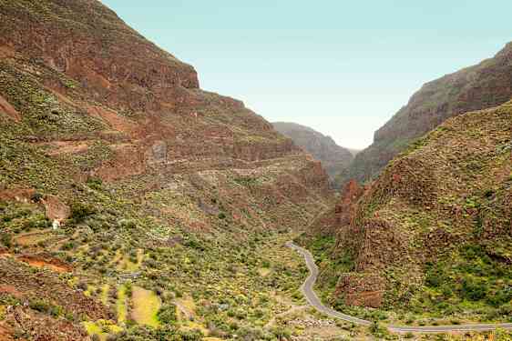 Kapea tie mutkittelee laakson läpi, jota ympäröivät jyrkät vuoret vihreän kasvillisuuden peittämänä. (Tekoälyn luoma teksti)