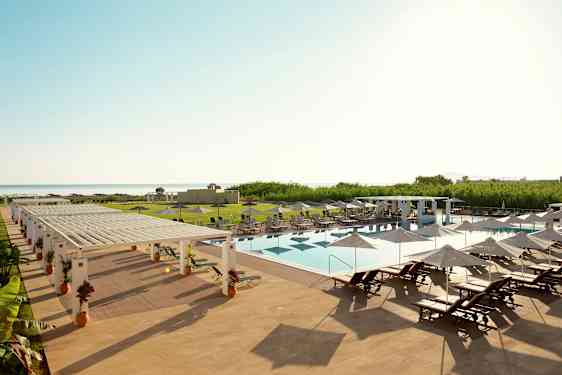 Ulkouima-allas, jossa aurinkotuoleja ja aurinkovarjoja hotellialueella lähellä merta. (Tekoälyn luoma teksti)