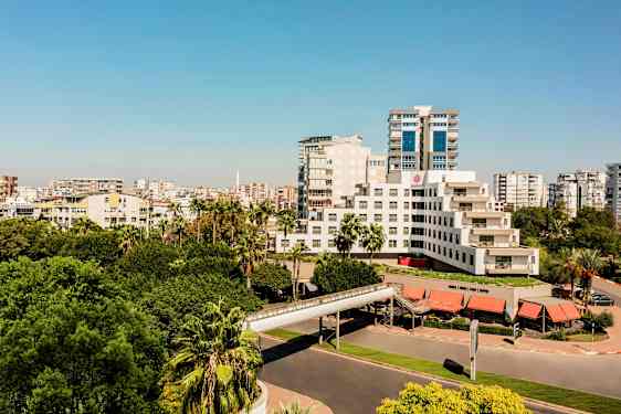 Nykyaikainen rakennus, jota ympäröivät vehreät puut ja kaupunkiympäristö. (Tekoälyn luoma teksti)