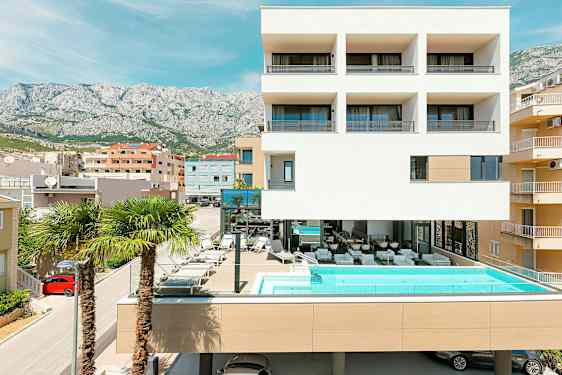 Nykyaikainen rakennus, jossa uima-allas ja palmuja edessä. (Tekoälyn luoma teksti)