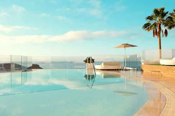 Äärettömyysallas merinäköalalla, ympäröitynä aurinkotuoleilla ja palmuilla. (Tekoälyn luoma teksti)