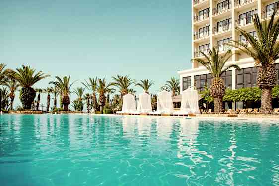 Ulkouima-allas, jonka taustalla on hotelli ja ympärillä palmuja. (Tekoälyn luoma teksti)