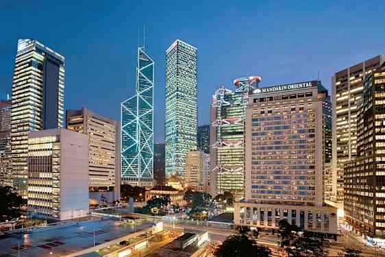 Kaupunkinäkymä, jossa korkeita rakennuksia valaistu iltavalossa. (Tekoälyn luoma teksti)