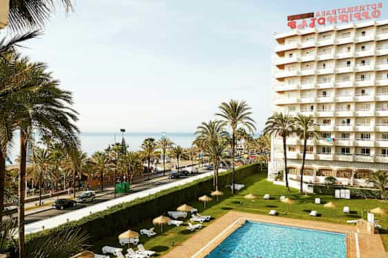 Kuva hotellista, jossa on uima-allas, palmuja ja näkymä merelle. (Tekoälyn luoma teksti)