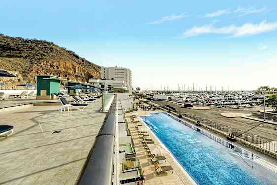 Uima-allasalue aurinkotuoleineen venesataman ja vuoren rinteen vieressä. (Tekoälyn luoma teksti)