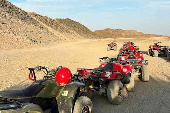 Jono mönkijöitä on pysäköity aavikkotielle, ympärillä hiekkaisia kukkuloita. (Tekoälyn luoma teksti)