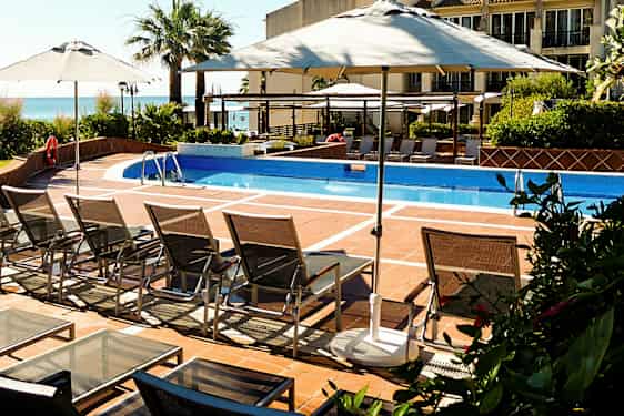 Ulkouima-allas, jossa on aurinkotuoleja ja aurinkovarjoja. (Tekoälyn luoma teksti)