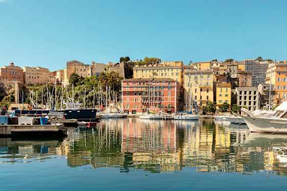 Satama, jossa on erivärisiä rakennuksia ja veneitä laiturilla. (Tekoälyn luoma teksti)