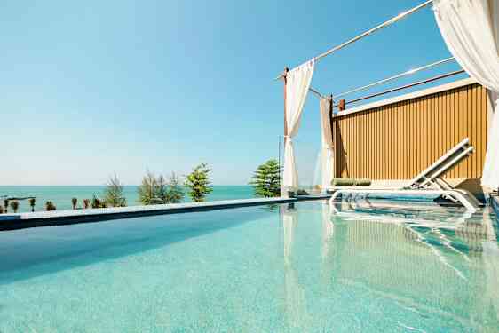 Ylellinen uima-allas, jonka vieressä on aurinkotuoli ja taustalla merinäköala. (Tekoälyn luoma teksti)