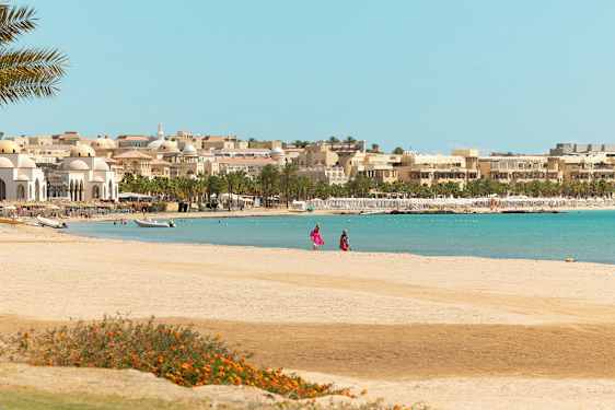 Ranta, taustalla rakennuksia ja palmuja. (Tekoälyn luoma teksti)