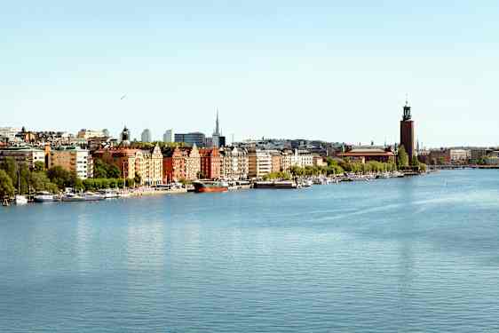 Kaupunkimaisema vesielementin vieressä, etualalla rakennuksia ja veneitä. (Tekoälyn luoma teksti)