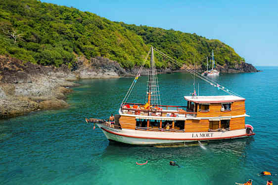 Puinen vene nimeltä La Moet on kiinnitetty turkoosiin veteen lähellä metsän reunustamaa rantaa. (Tekoälyn luoma teksti)