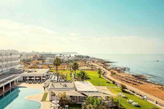 Kuva, joka esittää hotellialuetta uima-altaalla ja viheralueilla lähellä merta. (Tekoälyn luoma teksti)