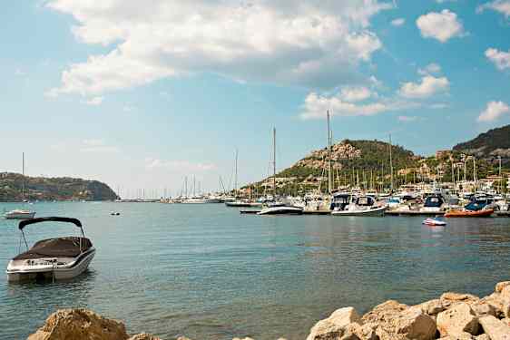 Kuva satamasta, jossa on veneitä ja taustalla vuoria. (Tekoälyn luoma teksti)