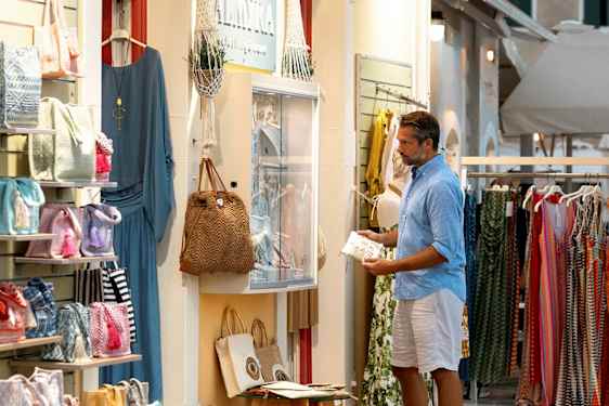 Kauppa kadun varrella, jossa myydään vaatteita ja asusteita, laukkuja ja mekkoja näkyvissä näyteikkunassa. (Tekoälyn luoma teksti)