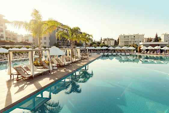 Uima-allas, jossa aurinkotuoleja ja aurinkovarjoja lomakeskuksen ympäristössä. (Tekoälyn luoma teksti)