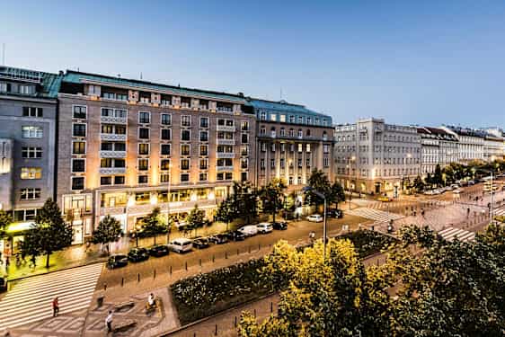 Kaupunkinäkymä, jossa on rakennuksia, aukio, valaistus ja puita. (Tekoälyn luoma teksti)