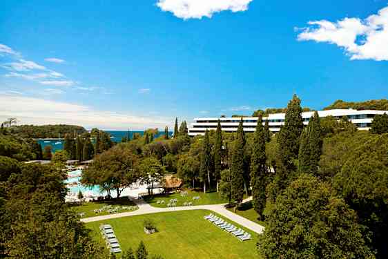 Hotellirakennus, jota ympäröivät mäntymetsät ja vihreät alueet, merinäköalalla. (Tekoälyn luoma teksti)