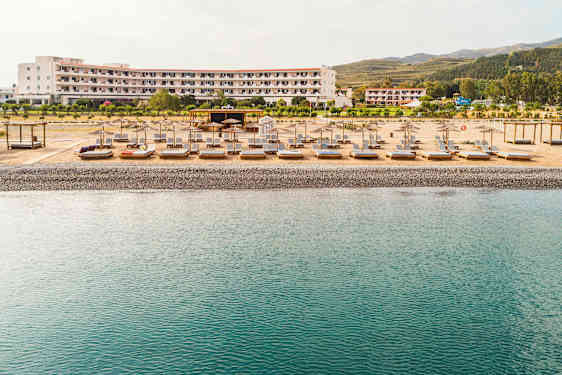 Ranta, jolla aurinkotuoleja ja varjoja hotellin edustalla. (Tekoälyn luoma teksti)