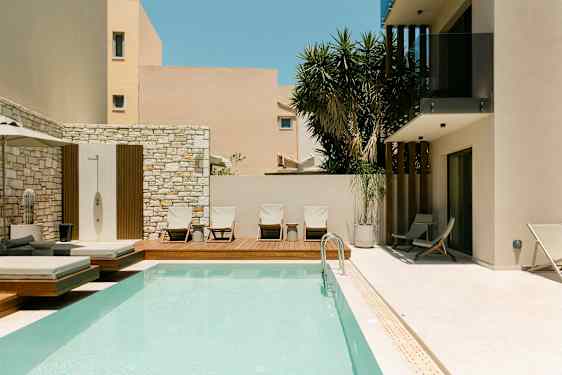 Ulkouima-allas ja aurinkotuoleja modernin rakennuksen vieressä. (Tekoälyn luoma teksti)