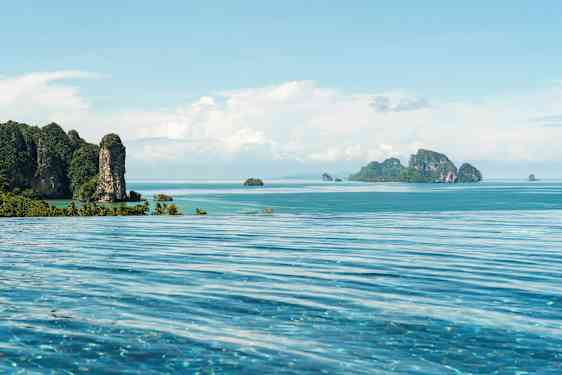 Infinity-allas etualalla, näkymä trooppiselle rannikolle ja merelle, jossa vuoristoisia saaria. (Tekoälyn luoma teksti)