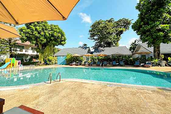 Ulkoallas, jossa on aurinkotuoleja ja leikkipaikka taustalla. (Tekoälyn luoma teksti)