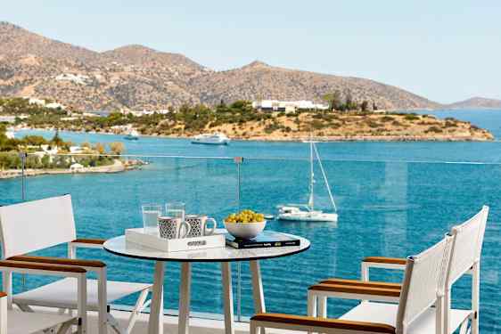 Terassi, jolla on pöytä ja tuoleja, tarjoaa näkymät merelle ja saarelle. (Tekoälyn luoma teksti)