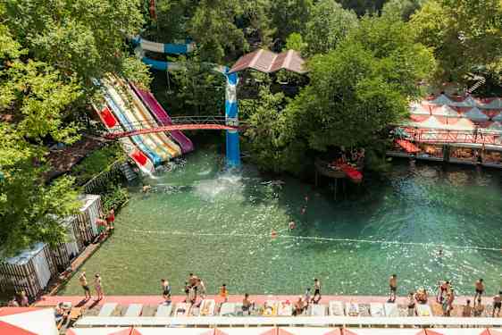 Vesipuisto, jossa on useita vesiliukumäkiä ja uintialue vehreyden ympäröimänä. (Tekoälyn luoma teksti)