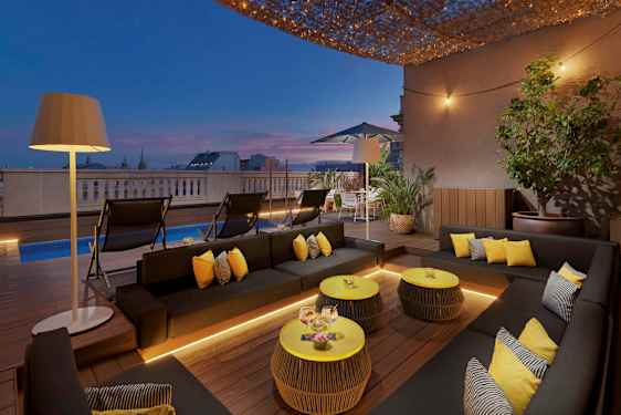 Terassi, jossa on modernit huonekalut, uima-allas ja valaistus iltahämärässä. (Tekoälyn luoma teksti)