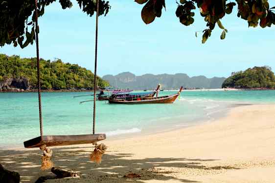 Ranta, jossa keinu ja puuvene vedessä metsän peittämien saarten edustalla. (Tekoälyn luoma teksti)