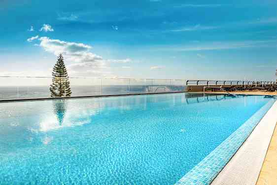 Kattouima-allas kirkkaalla sinisellä vedellä ja näkymä taivaalle ja puuhun. (Tekoälyn luoma teksti)