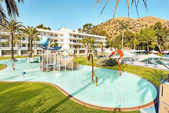 Lastenallas, jossa on vesileikkejä, ja hotellirakennus taustalla. (Tekoälyn luoma teksti)