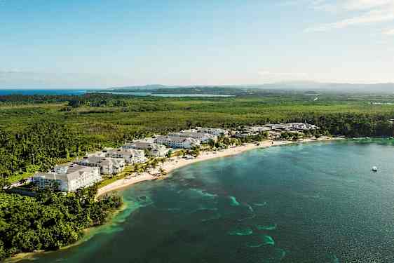 Näköala rannikkokaistaleelle, jolla on lomakohde, ympäröitynä vehreydellä ja merellä. (Tekoälyn luoma teksti)